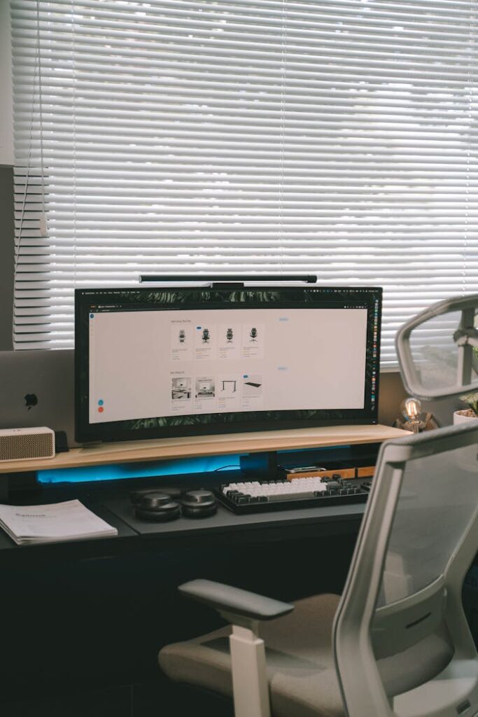 Modern home office setup featuring a sleek desktop and comfortable chair by a window.